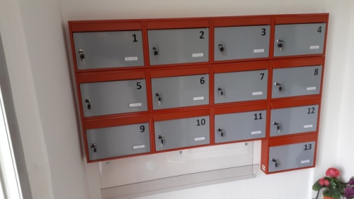 13 panelákových poštových schránok v kombinácii červenej a šedej.