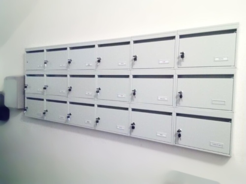 Sivé panelákové poštové schránky v bloku 3x6